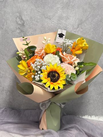 Bright mixed flower bouquet with sunflowers and roses wrapped in green and peach paper.