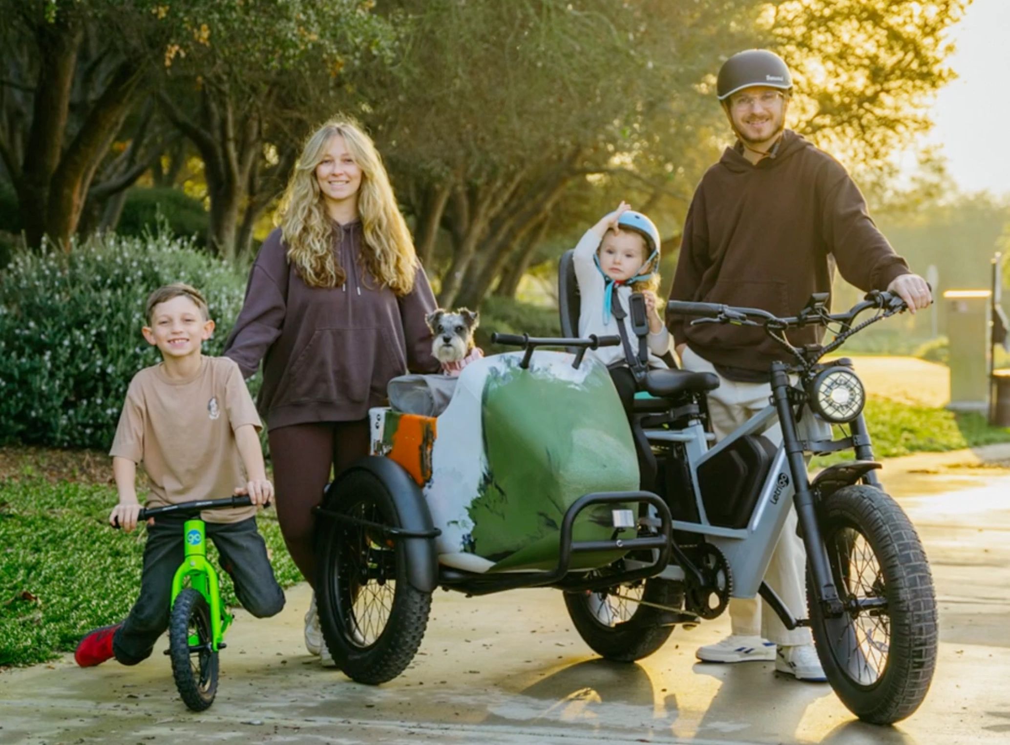 A family enjoying a bike ride with a child in a sidecar and a dog.