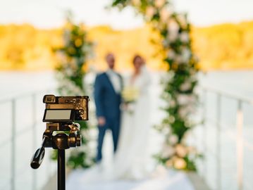 A video camera is filming the bride and groom at the off-site ceremony.