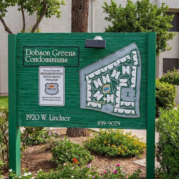 Dobson Greens Condominiums entrance sign with neighborhood watch notice and map.