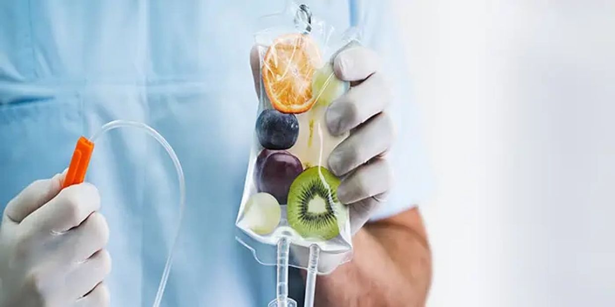 IV bag filled with various fruits held by a gloved hand.