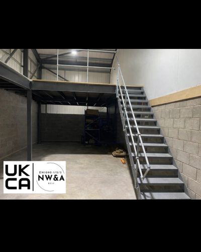 Industrial metal staircase leading to a mezzanine platform in a warehouse.