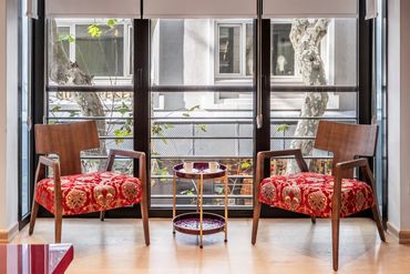Cozy seating area with two red velvet chairs and coffee cups by a large window. Istanbul luxury apartments, luxury living in Istanbul, Nişantaşı accommodation, Nisantasi living ın Nisantasi accommodation, Airbnb, Booking Istanbul