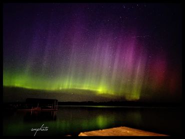 Aurora borealis lights up the night sky over a calm lake.