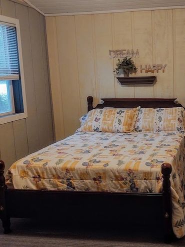 Cozy bedroom with floral bedding and wooden furniture under a ceiling fan.