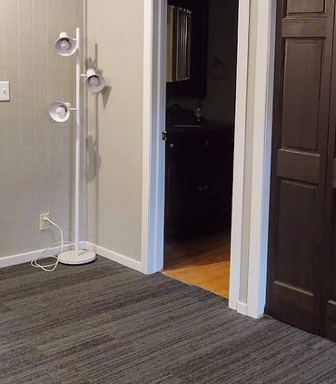 Empty room with dark wooden closet doors and a white standing lamp.