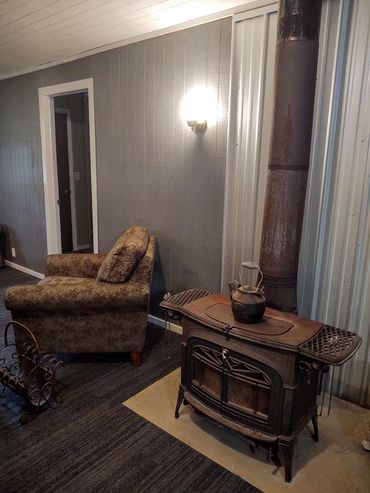 Cozy room corner with a vintage wood stove, armchair, and warm lighting.