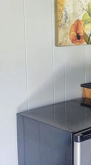 Compact kitchen corner with a mini fridge, microwave, and floral wall art.