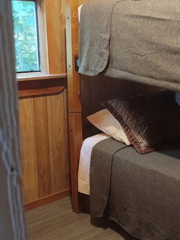 Cozy wooden room with bunk beds and plaid pillows.