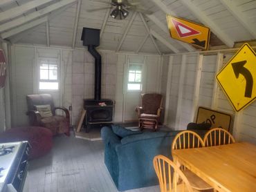 Rustic living space with road signs and cozy seating around a wood stove.
