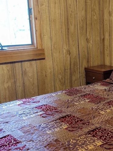 Cozy bedroom with rustic wood paneling and patterned bedding.