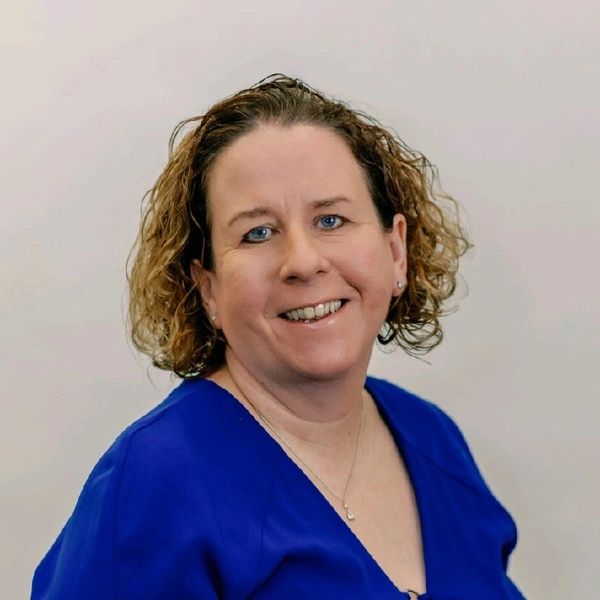 Smiling woman with curly hair in blue top.