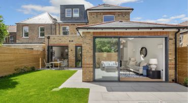 Modern brick house with large glass doors opening to a green backyard.