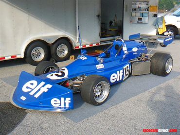 A blue race car parked in front of a truck