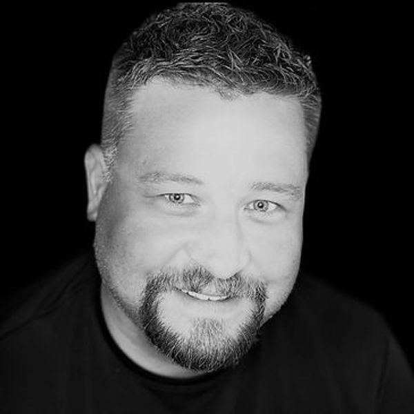 Black and white portrait of a smiling man with a beard and short hair.