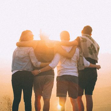 Supportive group hug with sunshine. Photo by Helena Lopes from Pexels.