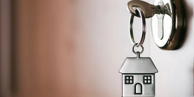 A house-shaped keychain hanging from a door lock key.