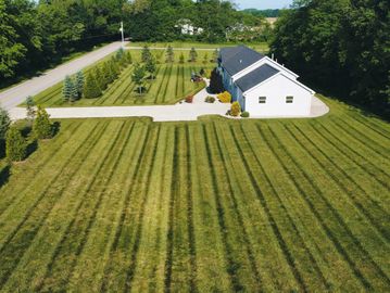 A large, neatly mowed lawn with striped patterns around a white house.