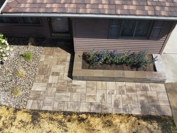 A house entrance with a tiled walkway and flower beds.