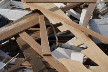 Pile of assorted wooden planks and debris scattered outdoors.