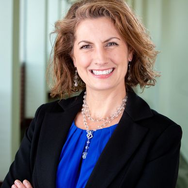 Confident woman in professional attire smiling at the camera.