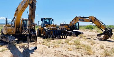 Three excavators and heavy machinery on a dry, grassy construction site.