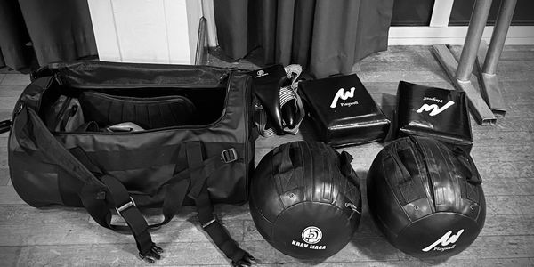 Black and white photo of Krav Maga training gear laid out on the floor.