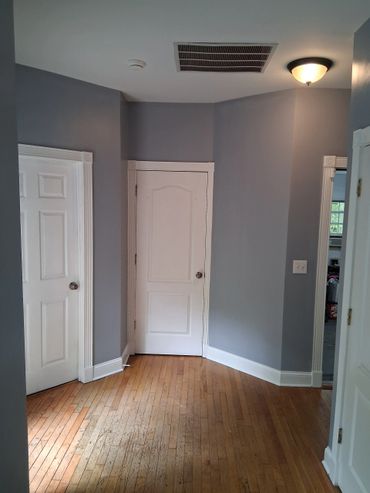 Empty hallway with three white doors and hardwood floors.