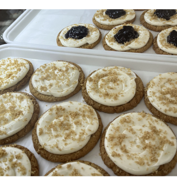 Cookies with cream frosting and some with jam topping.