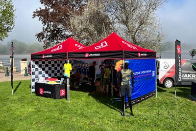 Outdoor promotional booth with mannequins displaying sportswear under red tents.