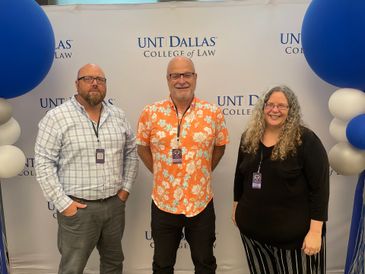 Three people posing at UNT Dallas College of Law event with balloons.