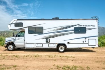 White Sunseeker RV parked on dirt road.