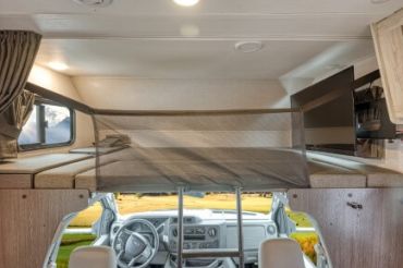 Interior of a camper van with loft bed and TV.