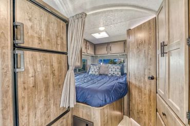 Cozy RV bedroom with wood accents and navy bedding.