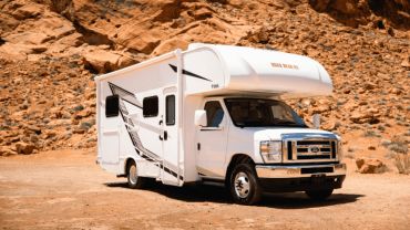 White RV parked in a rocky desert landscape.