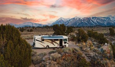 RV parked in a scenic mountainous landscape at sunset.