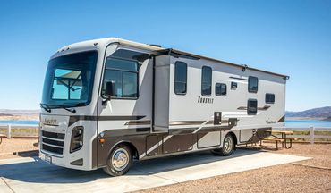 A large RV parked at a scenic campsite by a lake.