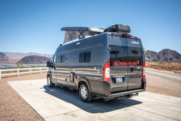 Black camper van parked in a desert landscape.