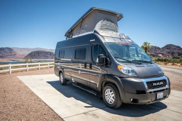Black camper van with raised roof parked outdoors.