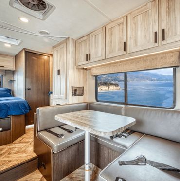 Cozy RV interior with dining area and ocean view.