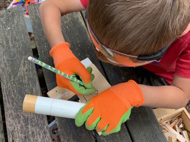 child wearing safety gloves & goggles as he measures a hole