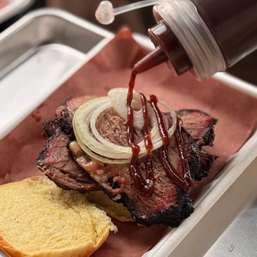 Barbecue beef sandwich with onions and sauce on a bun.