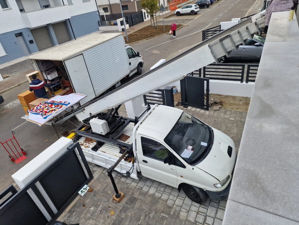 Un autoscala posizionata davanti una finestra per un trasloco, nello sfondo un furgone aperto