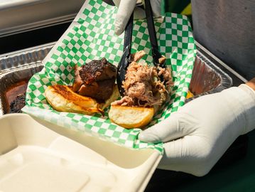 Serving pulled pork sandwich with bun and side.