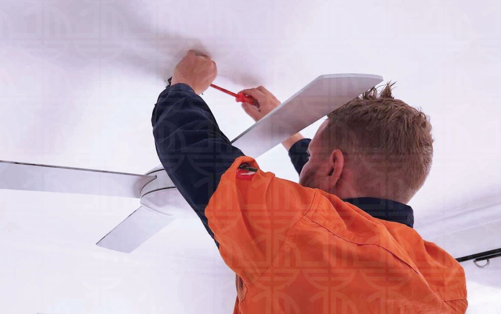 Technician installing a ceiling fan with a screwdriver.