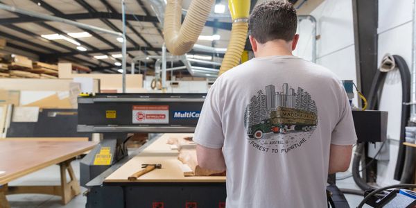 Person wearing a Madera Arts shirt working in a woodworking shop.