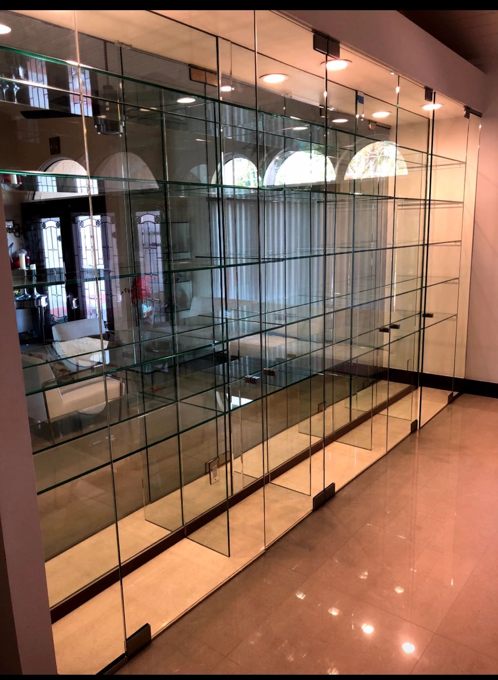 Floor to ceiling wall mirror with custom glass shelves and glass doors.