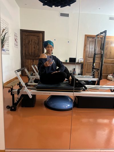 Isma, owner and instructor at Pilates Station, taking a mirror selfie while on the reformer.