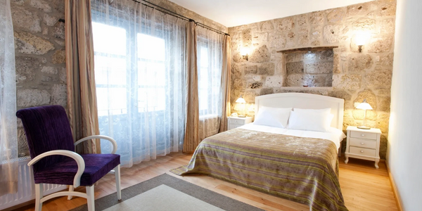Cozy bedroom with stone walls, a purple chair, and soft lighting.