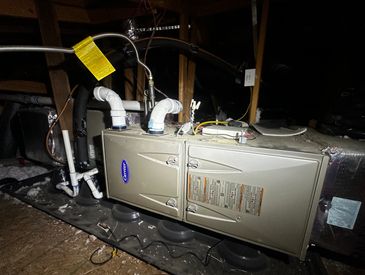 A heating and air conditioning unit installed in a dimly lit attic space.